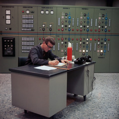 A man at a desk, behind him a control centre in the Refinery du Rh?ne, Collombey-Aigle.